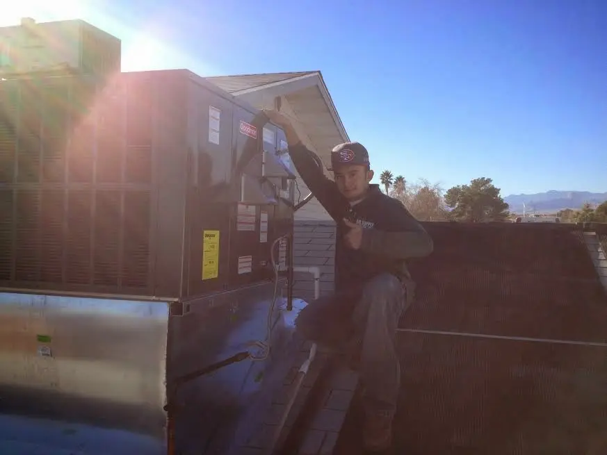 HVAC technician performing Air Duct Cleaning on a rooftop unit in Farmersville